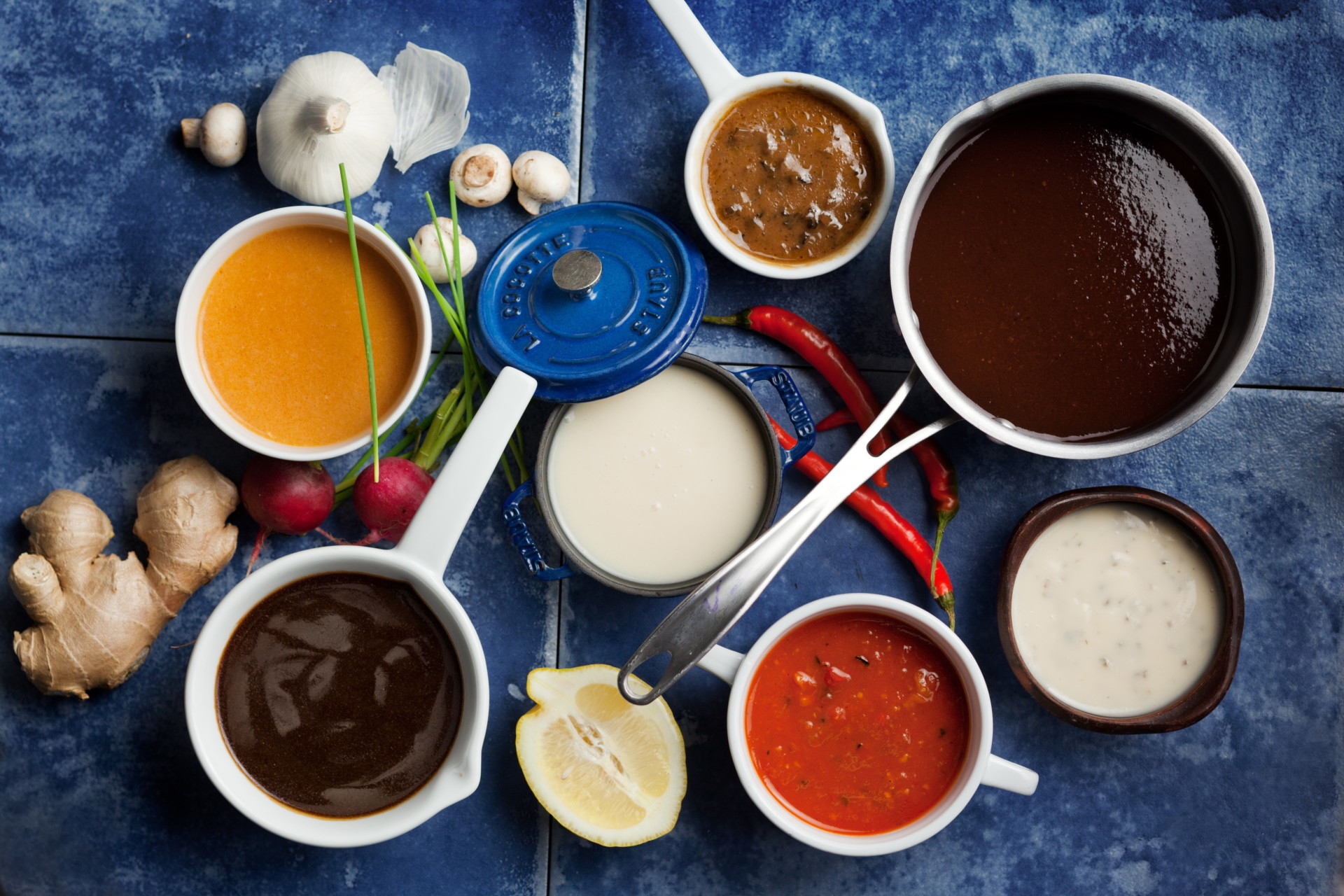 demi glaze surrounded by many other sauces on blue tiles