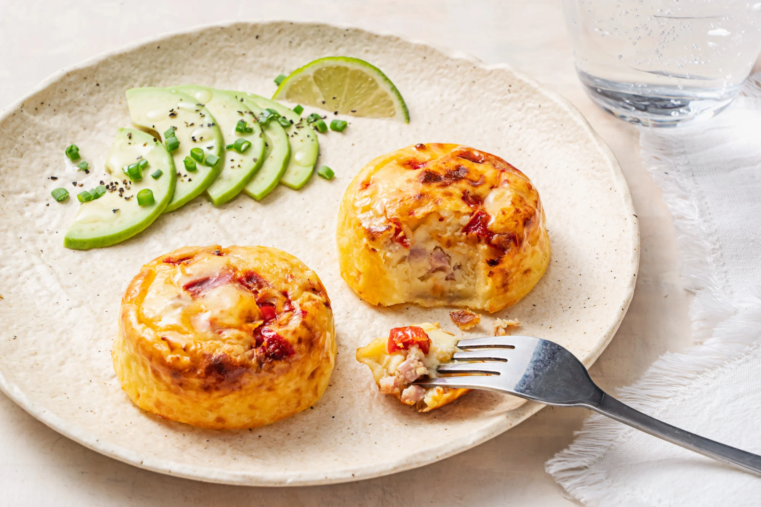 Ham and Pepper egg bite served on a white plate with a side of sliced avocado